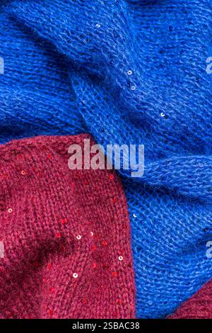 Red and blue knitted sweater with sequins. Sequinned knitwear. Sequin pattern in needlework. Knitting hobby. Knitter work. Sequins texture in knitwear Stock Photo
