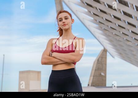 Confident Athletic Woman Posing Outdoors with Modern Architecture in Background Stock Photo