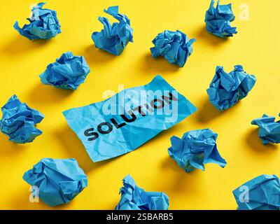 To search for or find a solution for a problem. The word solution on piece of paper among the crumpled blue paper balls. Stock Photo