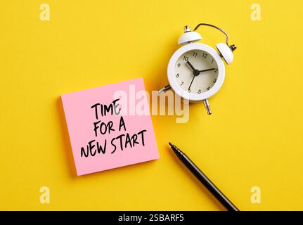 Time for a New Start message on pink note paper with alarm clock and pen. New beginnings in business career or life concept. Stock Photo