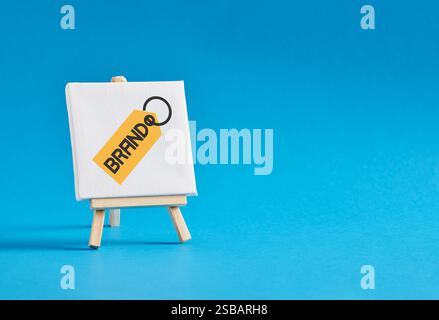 Keychain with the word brand on an easel against blue background. Branding, brand building, recognition or awareness, business marketing concept. Stock Photo