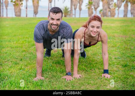Fit couple exercising outdoors doing push-ups on the grass in a park Stock Photo
