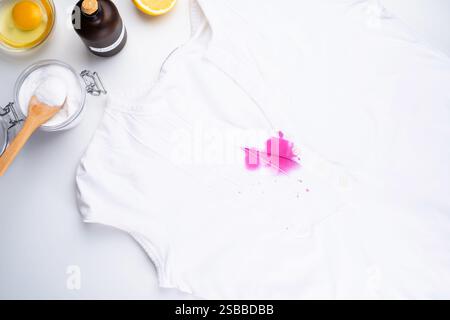 Cleaning a pink pomegranate juice stain from a white fabric with baking soda and vinegar in a light kitchen.  Stock Photo