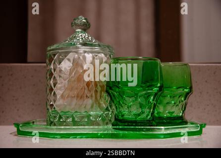 Two green drinking glasses and canister on bathroom counter Stock Photo