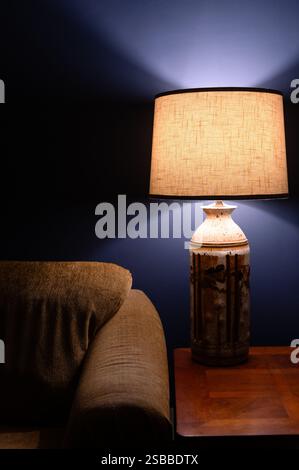 Table lamp next to gold couch and a blue wall Stock Photo
