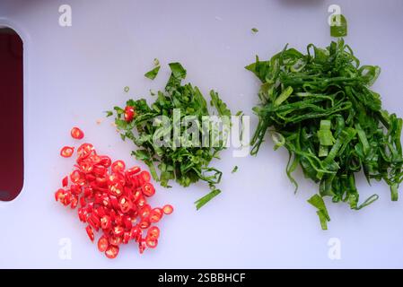 Top view of chili pepper, celery, and  leek slices on a white cutting board. Stock Photo