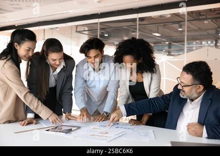 Positive diverse different aged colleagues analyzing statistic paper reports together Stock Photo