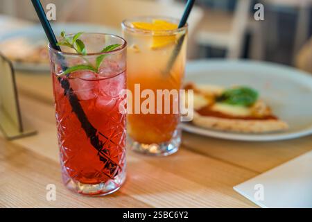 Two mocktails, Cinderella with grenadine and raspberry lemonade, on a wooden table in soft focus.  Stock Photo