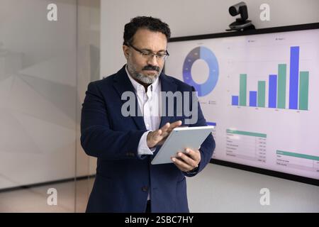 Serious senior Indian business leader man analyzing marketing data Stock Photo