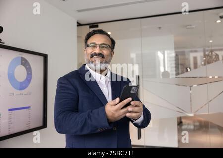 Cheerful mature Indian company director man using modern technology Stock Photo