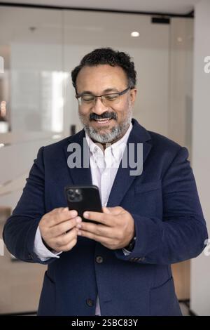 Happy senior Indian executive man using mobile phone Stock Photo
