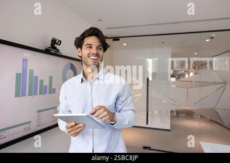 Cheerful young Latin startup leader man working with tablet Stock Photo