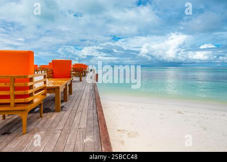 Scenic view of wooden furniture on terrace in Maldives with turquoise water and dramatic sky Stock Photo