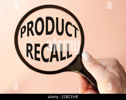 Product recall symbol. Concept words Product recall on magnifying glass. Beautiful pink background. Businessman hand. Business and Product recall conc Stock Photo