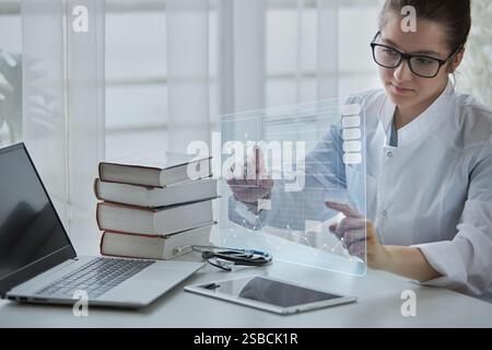 Female doctor uses modern technologies, virtual screen with hologram. Concept of medicine of the future. Stock Photo