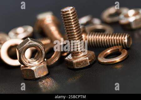 Copper plated bolts, nuts and washers on dark background Stock Photo