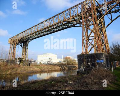 Rusty historic transporter bridge Warrington over a tranquil river under a blue sky. Stock Photo