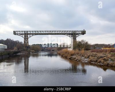 Historic bridge spanning over a calm river during a cloudy day. Warrington transporter bridge. Stock Photo