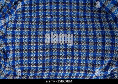 A close-up view of checkered boucle blue and black fabric with intricate texture and soft folds.  Stock Photo