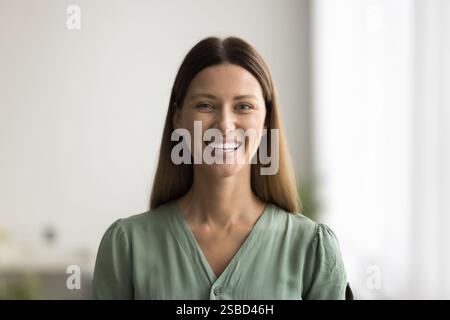 Headshot portrait of beautiful young woman smiles directly at camera Stock Photo