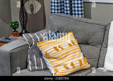 Two grey and orange pillows on couch sofa in modern apartment, house or home with staging of large gray furniture Stock Photo