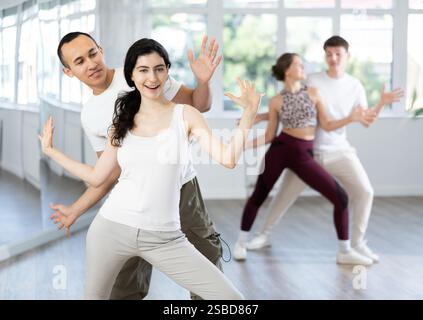 Cheerful young couple practicing playful Charleston in dance studio Stock Photo