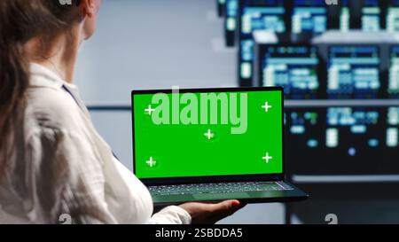 Licensed tech support in server farm housing high end supercomputers capable of quickly and efficiently performing complex computations and data analysis, using mockup laptop to remove dangers Stock Photo