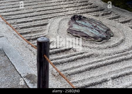 A single rock sits amid a geometric pattern of raked white sand in a mini karesansui (dry landscape garden) at Ginkakuji Temple, Kyoto, Japan. Stock Photo