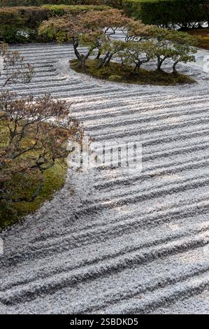 Island group of moss and shrubs sits amid a sea of raked white sand in a linear geometric pattern at Ginkakuji Zen Buddhist Temple, Kyoto, Japan. Stock Photo