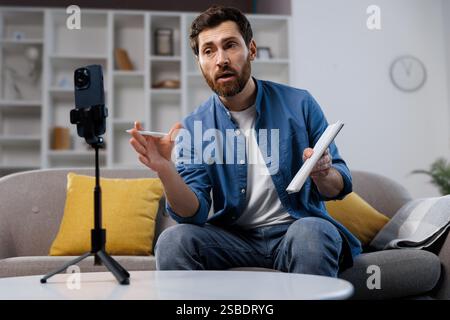 online broadcast, lesson, video call, Engaging virtual meeting with a presenter discussing ideas while using a tablet in a modern living room setting Stock Photo