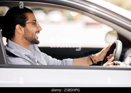 Handsome millennial arabic guy driving car, side view Stock Photo