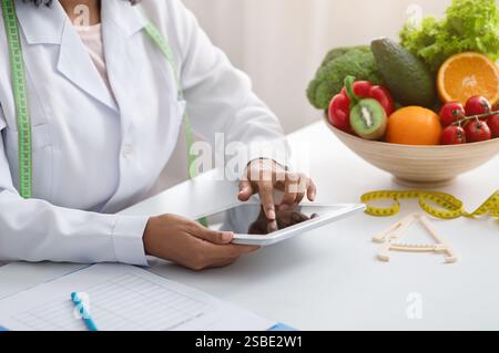 Dietologist black woman using digital tablet at workplace Stock Photo