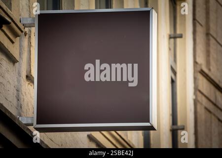 Selective blur on A rectangular black sign stands blank outside a store, contrasting with the building’s light facade. This uncluttered design is read Stock Photo