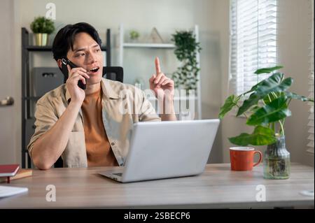 A professional Asian businessman is handling business over the phone in his office, talking on the phone, discussing work on the call. businesspeople, Stock Photo