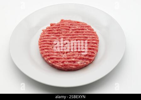 Fresh ground beef patty ready for grilling in a white dish. Stock Photo