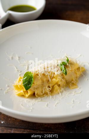 Delicious Italian pasta pappardelle with parmesan in white porcelain plate on wooden table Stock Photo