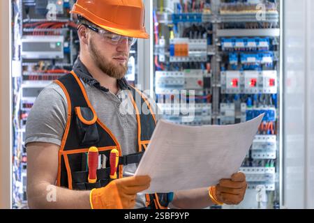 Electrician man in overalls works in the switchboard. Portrait of an electrician in overalls. Stock Photo