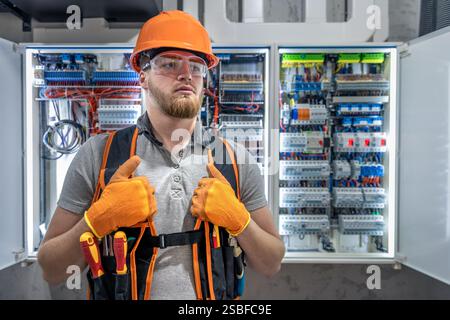 Electrician man in overalls works in the switchboard. Portrait of an electrician in overalls. Stock Photo