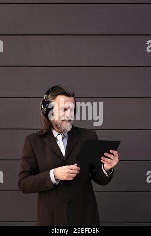 elegant mature man using tablet and headphones Stock Photo