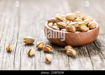 Pistachio nut in nutshell on wooden rustic backdrop in bowl, composition of pistachios great for healthy and dietary nutrition. Concept of nuts Stock Photo