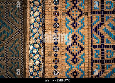Intricate tile work featuring geometric patterns in blue and white against a textured brick background. Stock Photo