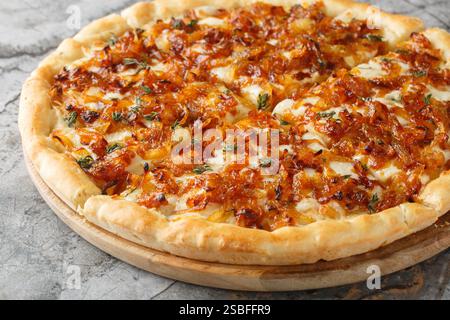 French Onion Pizza with lots of Gruyere and Mozzarella cheese, with thyme and garlic close-up on wooden board on table. Horizontal Stock Photo