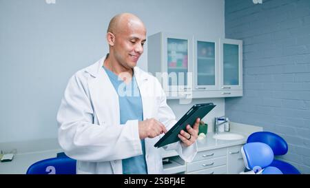 Professional Dentist Using a Tablet in a Modern Clinic Environment Stock Photo