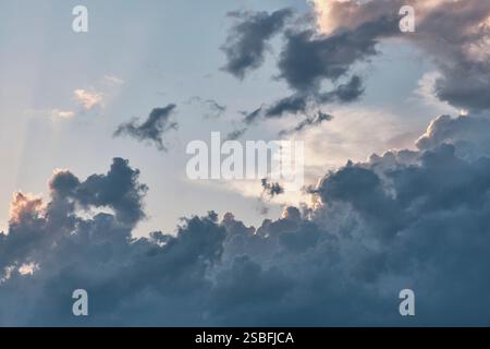 Stunning sky filled with dark, billowing clouds illuminated by soft sunlight. Contrast between deep shadows and glowing edges creates dramatic and moo Stock Photo