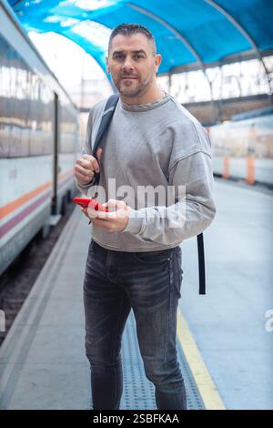 Man Using Red Smartphone at Train Station.Vertical Stock Photo