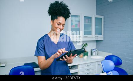 Confident Dental Professional Using Tablet in Modern Office Ready to Assist Patients Stock Photo