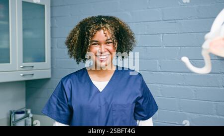 Smiling Female Healthcare Professional in Scrubs in a Dental Office Setting Stock Photo