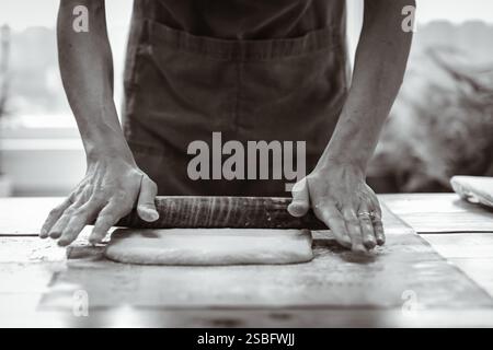 Artisan Baker Rolls Dough for Bread Preparation Stock Photo