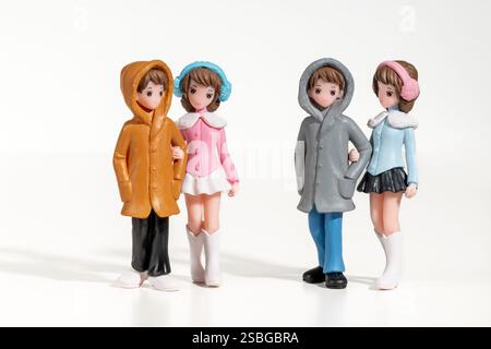 Miniature boyfriends and girlfriends are walking together arm in arm, wearing winter clothes Stock Photo