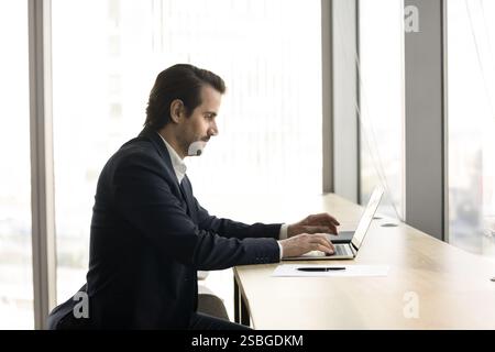 Young businessman in suit working on his laptop in workspace Stock Photo